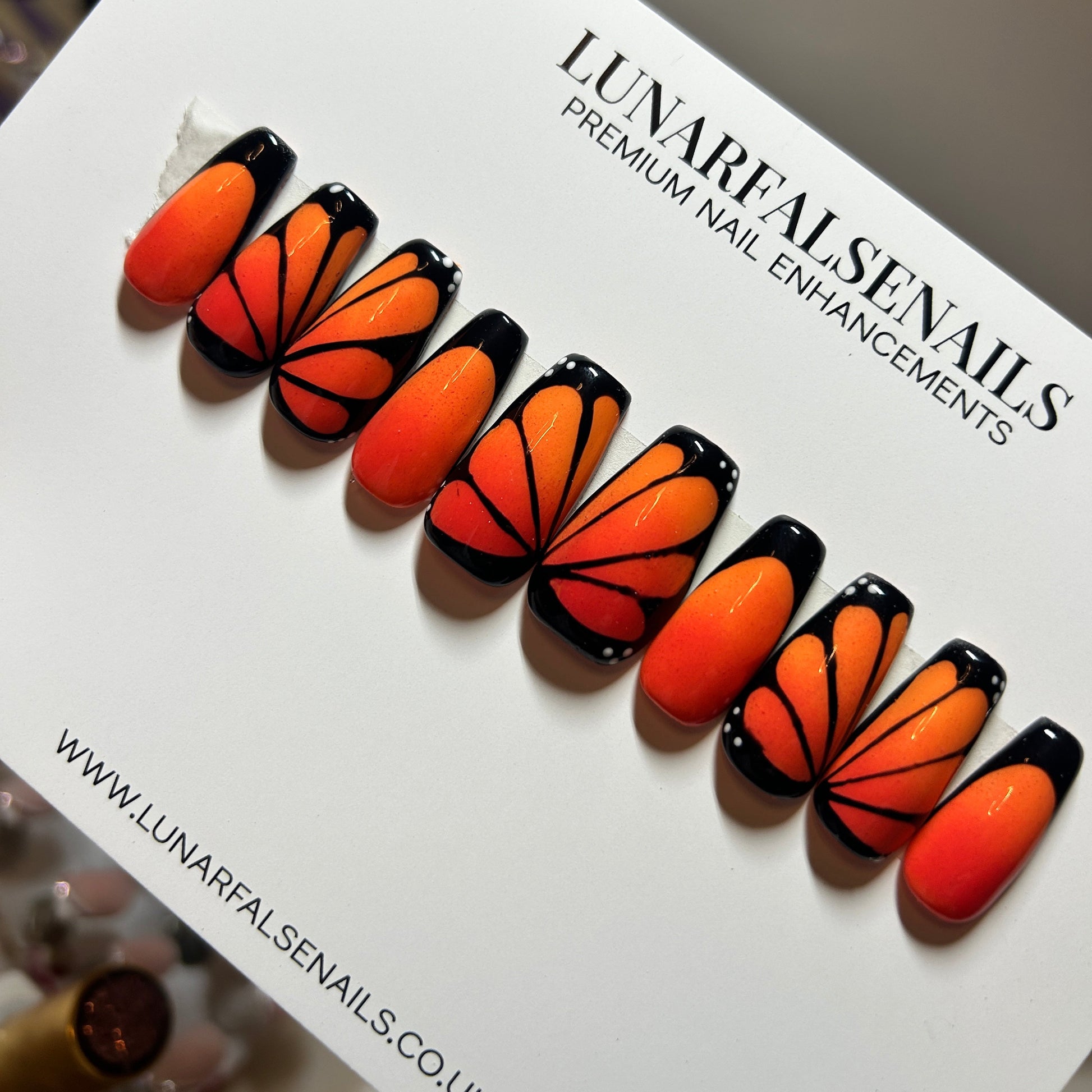 Butterfly-themed false nails on a branded card for Lunar Fake Nails.